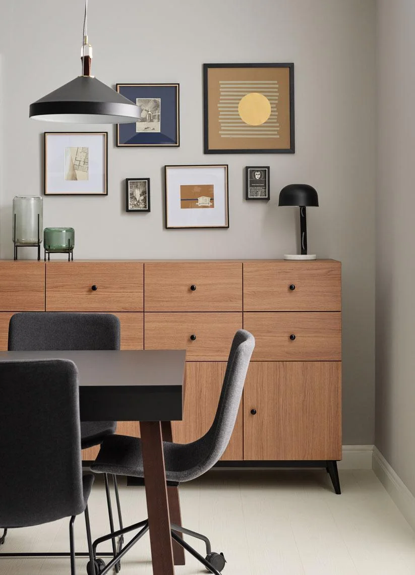 Elegancki salon z drewnianą komodą i minimalistycznymi obrazami.